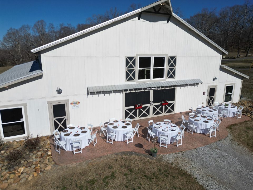 An aerial view of the Cedar Pond Farms barn with banquet tables set on the patio for a company retreat.