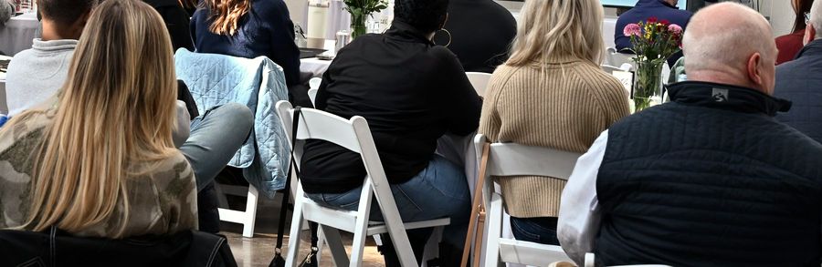 Colleagues seated at linen-covered round tables during a company meeting at Cedar Pond Farms.