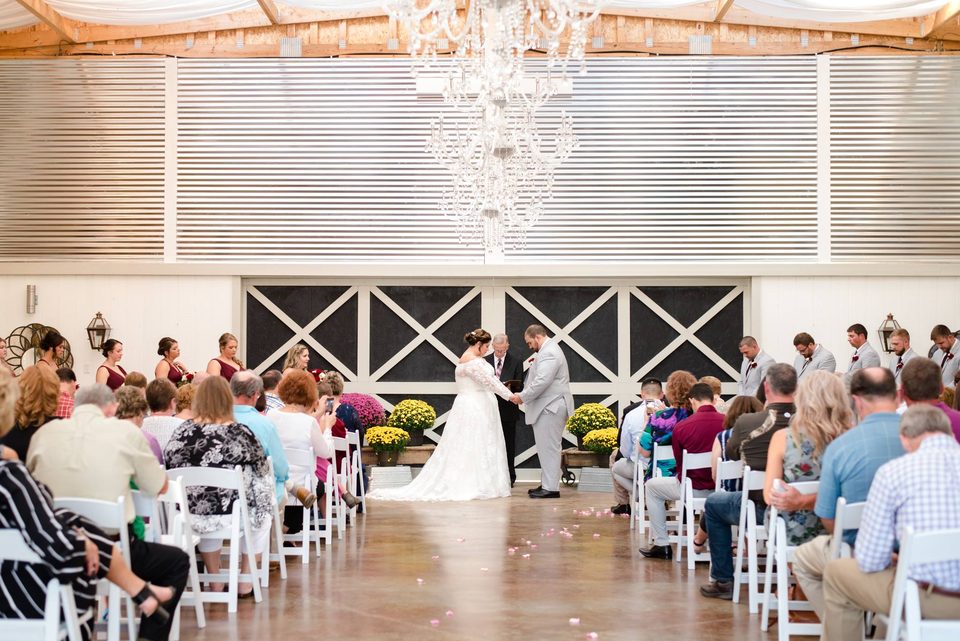 White chairs set under the chandelier inside the Grand White Barn for a full-service farm wedding near Knoxville