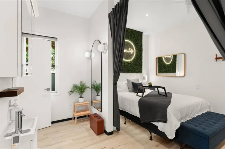 Enjoy this modern European one-bedroom suite in our barndominium at the fluffy cow farm just outside the Smoky Mountains — queen bed, glowing greenery wall and a dressing mirror by the door.
