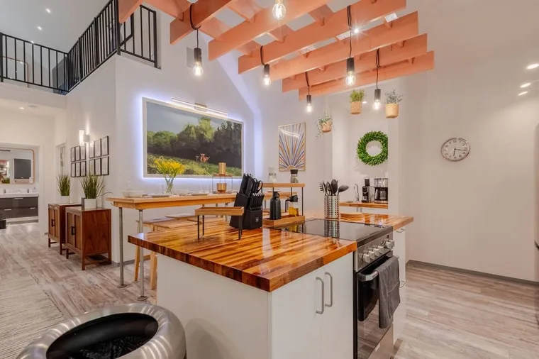 Cook beneath the coral beams and filament lights in this three-bedroom barndominium kitchen at Cedar Pond Farms, just outside the Smoky Mountains.
