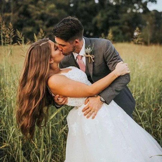 Una pareja besándose entre el pasto alto del Campo de Heno en esta granja en producción cerca de Sevierville