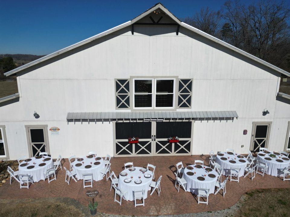 The Grand White Barn with round reception tables set on the front patio