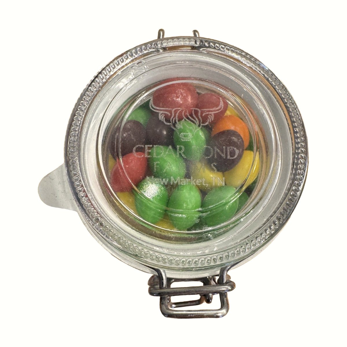 Small glass mason jar with metal clasp lid filled with colorful candy, viewed from above, labeled Cedar Pond Farms New Market TN.