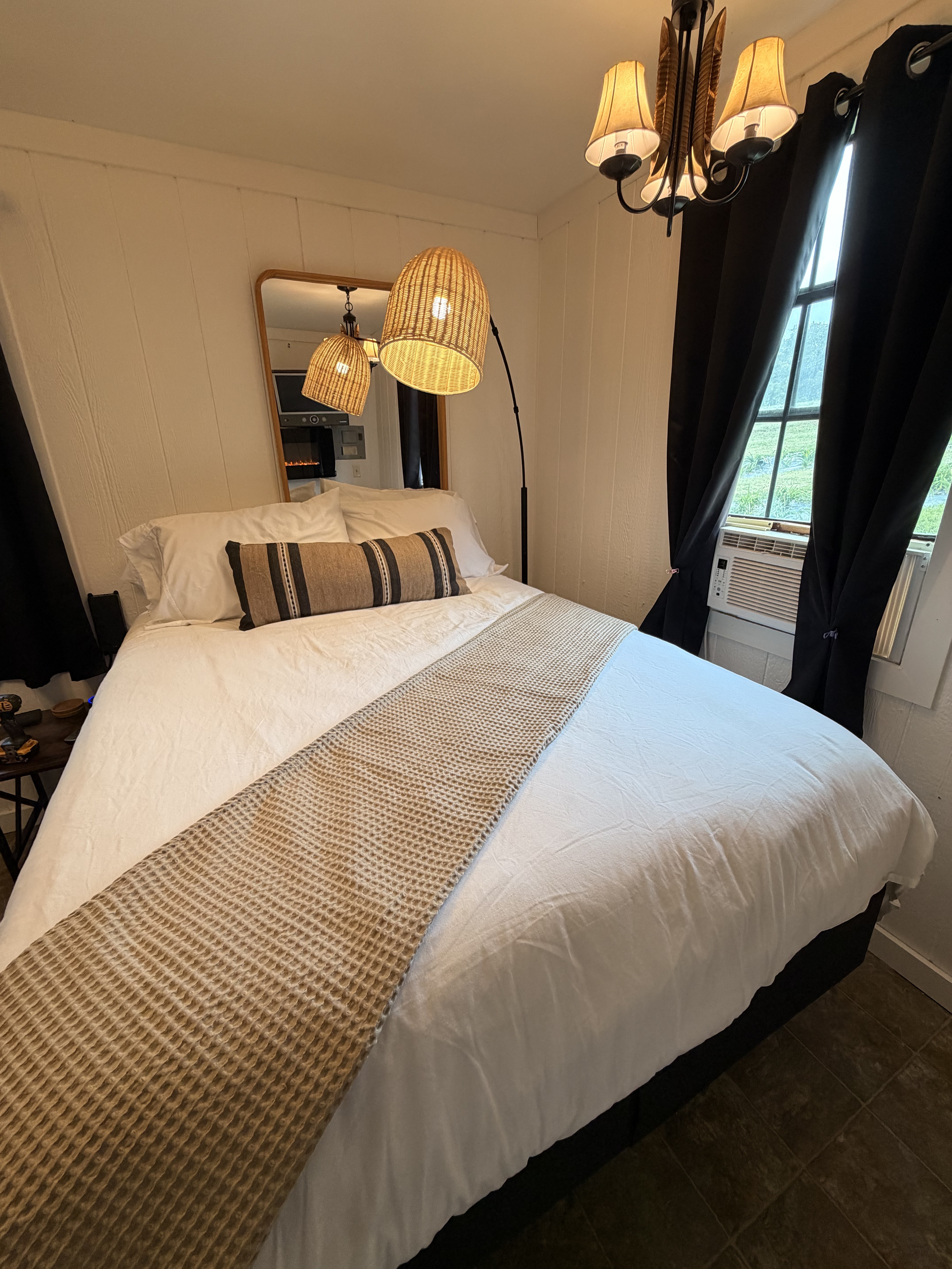 Cozy bedroom with plush linens, warm lighting, and in-room AC